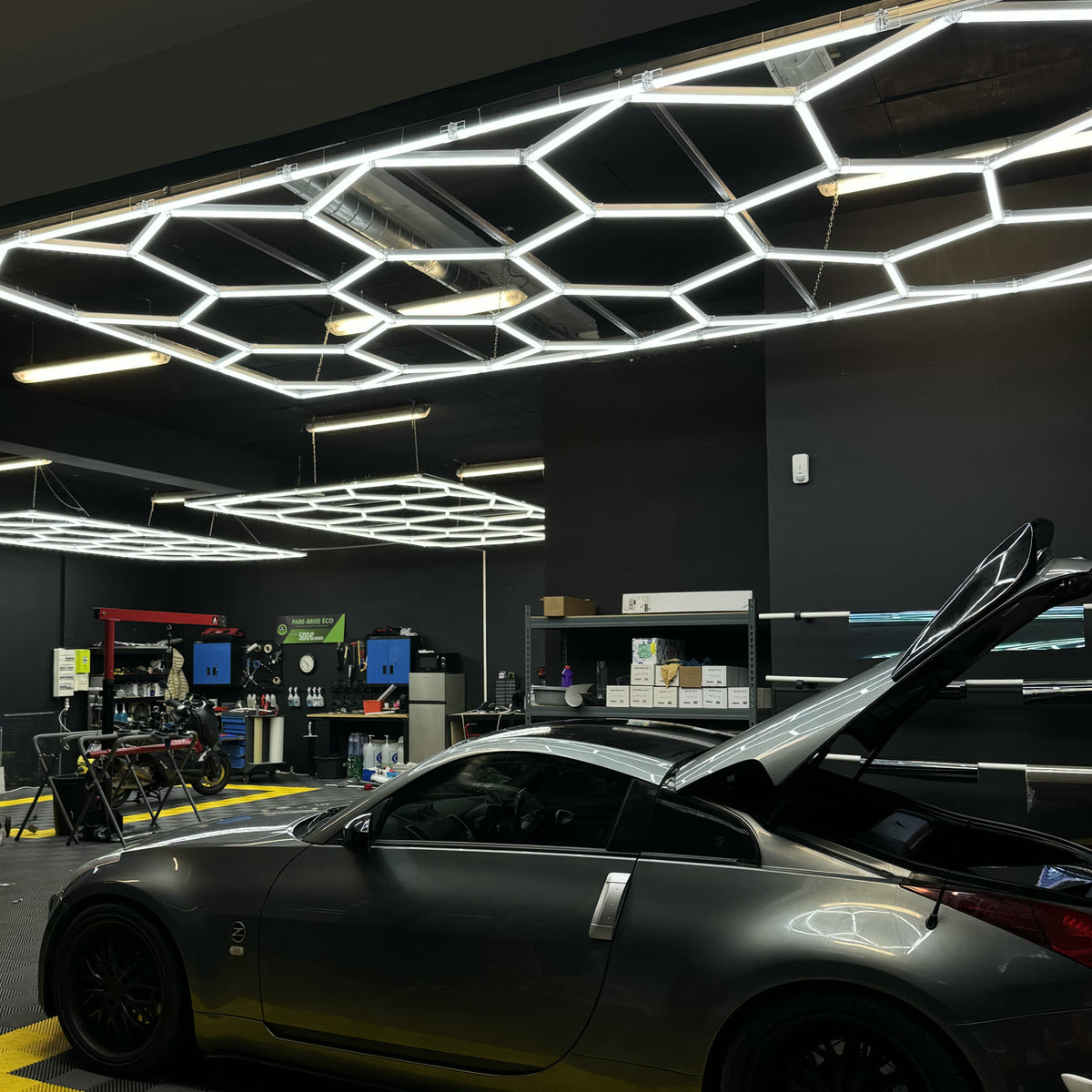 Garage éclairé par des kits LED hexagonaux, voiture grise capot ouvert