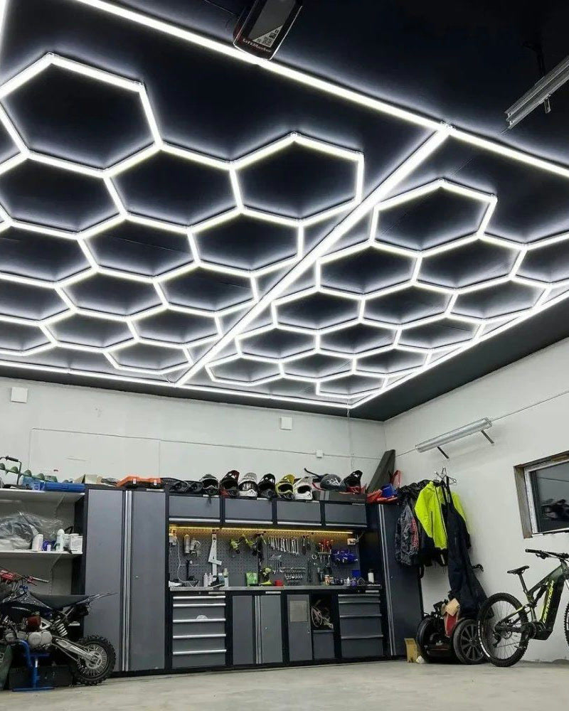 Garage avec un plafond LED hexagonal encadré, établi et motos